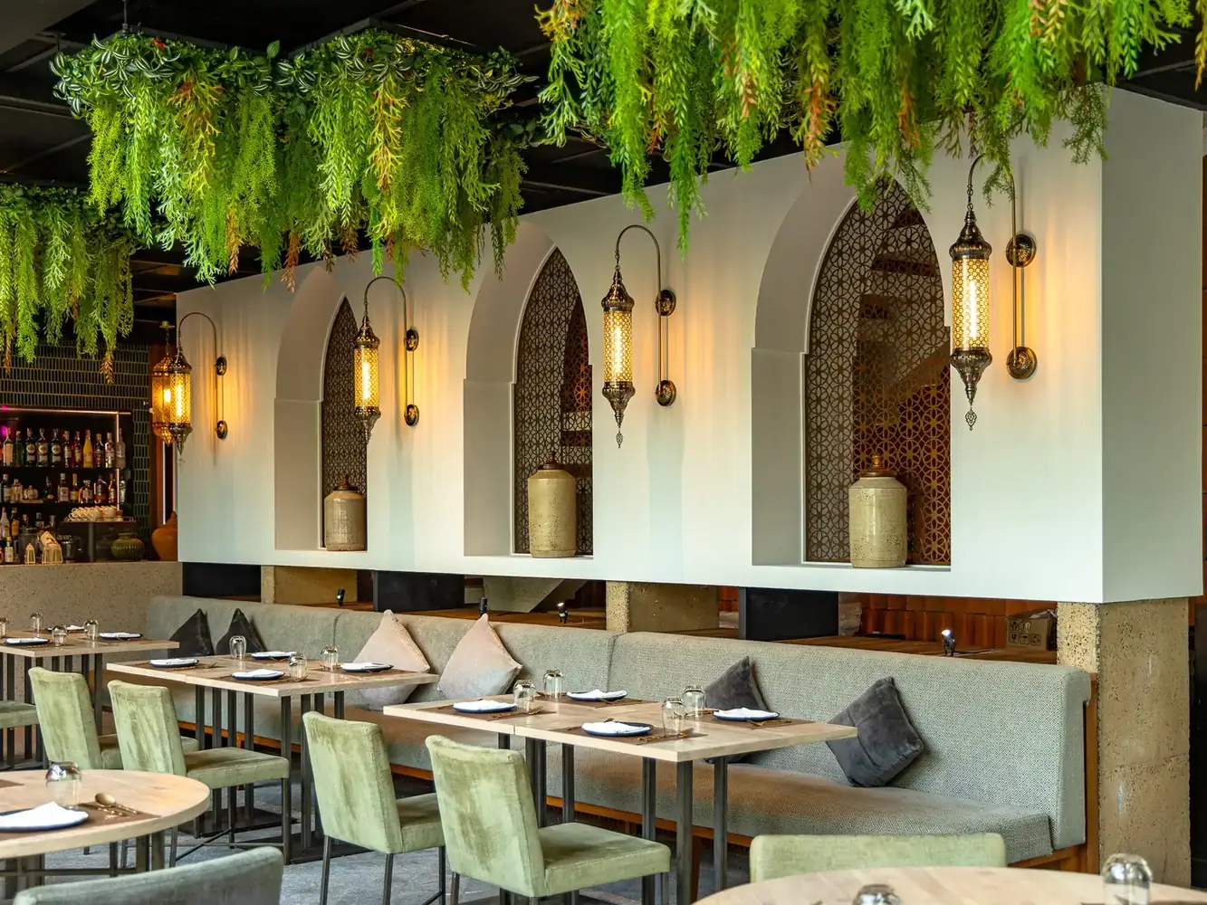 The dining room at Al Saray Sathorn, a halal Lebanese restaurant in Bangkok, with arched wall niches, brass lanterns and hanging greenery