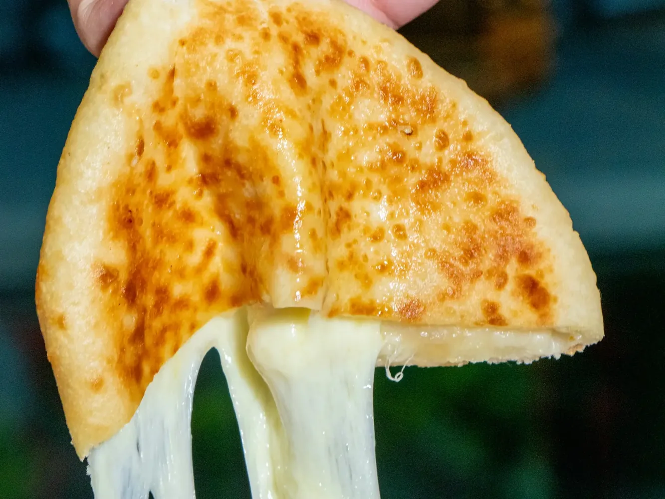 A cheese naan pulled apart with stretching melted cheese at Al Saray, a halal Indian restaurant in Silom, Bangkok